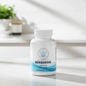 A white bottle of Balanced Botanicals Berberine Capsules stands on a light marble surface in a bright, modern interior setting with soft shadows and a blurred plant in the background.