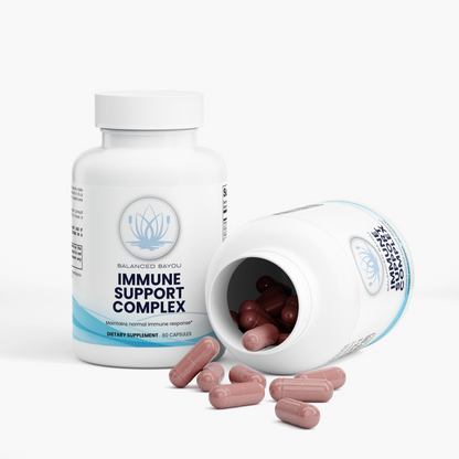 A white bottle of Balanced Botany Immune Support Complex dietary supplement, shown standing upright with several pinkish-brown capsules spilled out beside it on a clean white background.