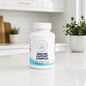 A white bottle of Balanced Bayou Immune Support Complex dietary supplement, placed on a white marble countertop with a blurred kitchen background and potted plants.