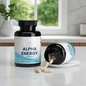 A bottle of Alpha Energy Capsules stands upright on a white marble countertop, with another bottle tipped over on a small white plate, showing beige capsules spilling out. The background is a softly blurred kitchen or bathroom setting with a window and greenery.