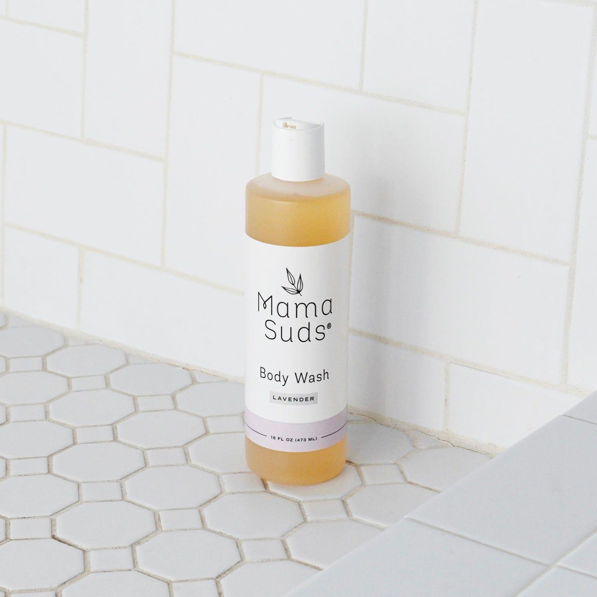Mama Suds body wash bottle on a tiled bathroom floor