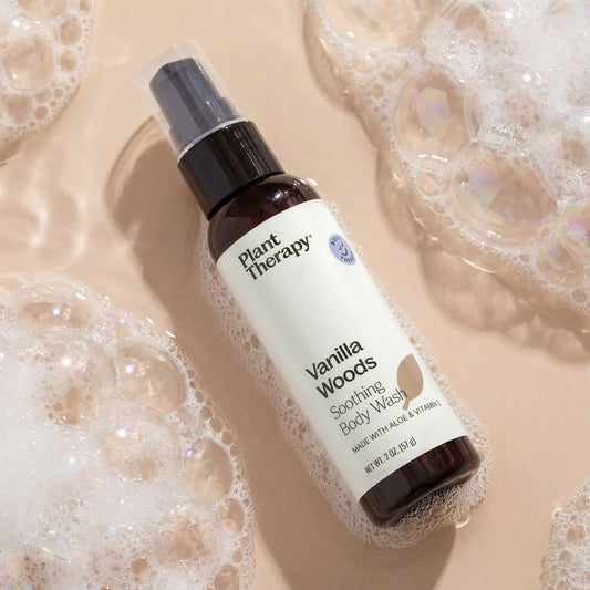 Plant Therapy Vanilla Woods Soothing Body Wash bottle on a beige background with soap bubbles