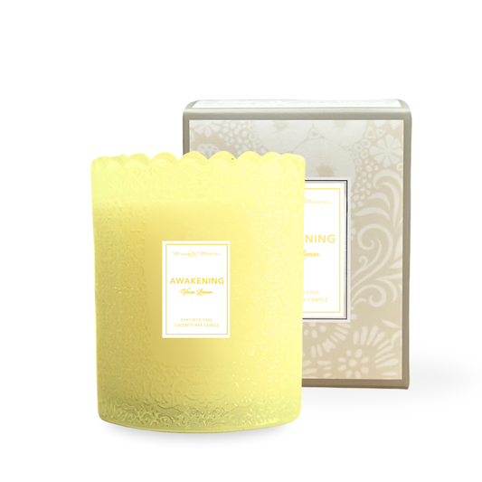 Yellow candle with a decorative label in front of a matching box on a white background
