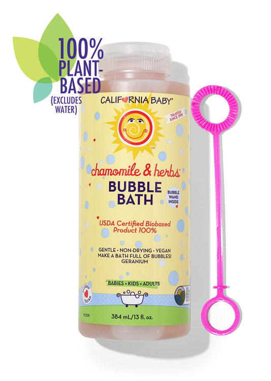 A bottle of California Baby Chamomile & Herbs Bubble Bath next to a bright pink bubble wand, set against a clean white background with a green '100% Plant-Based' graphic overlay.