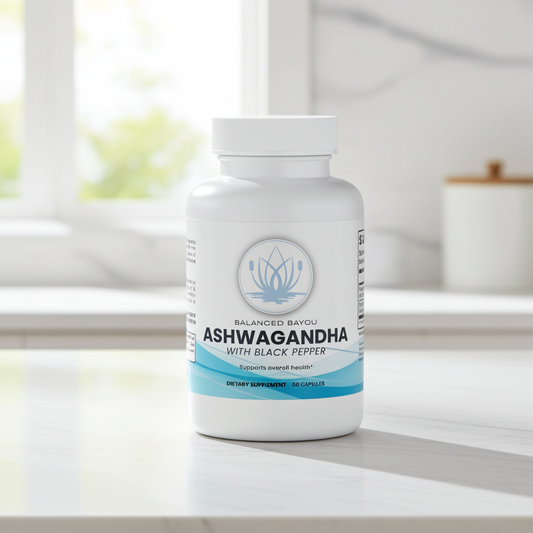 A white bottle of Balanced Bayou Ashwagandha with Black Pepper dietary supplement, placed on a light marble countertop in a bright kitchen setting.