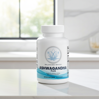 A white bottle of Balanced Bayou Ashwagandha Plus dietary supplement, placed on a light marble countertop with a blurred kitchen background.