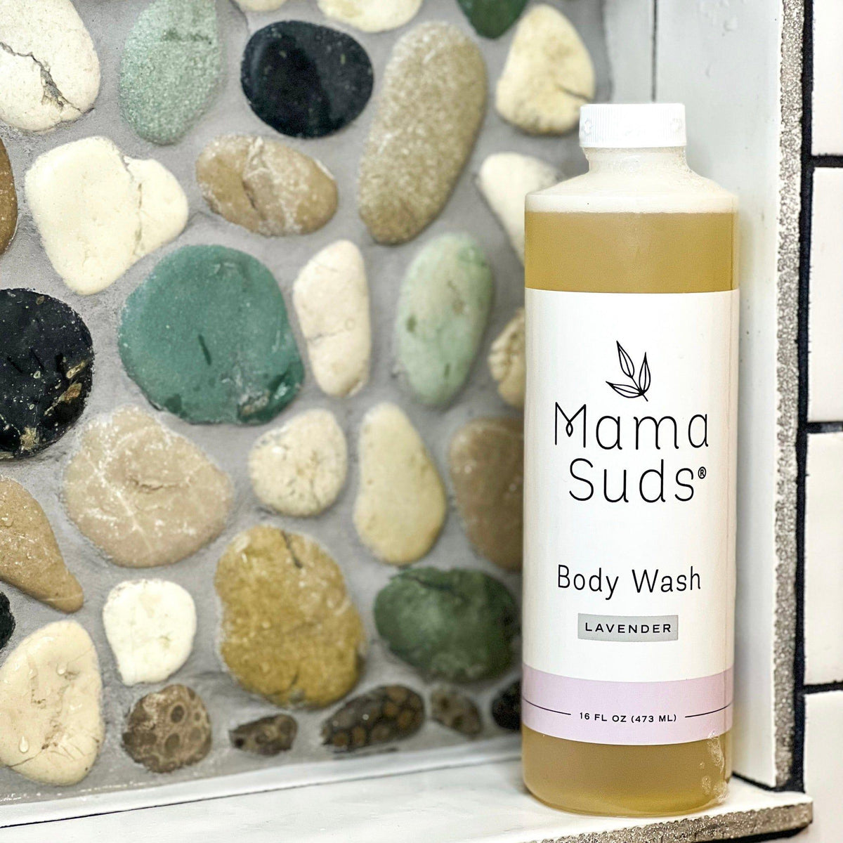 Mama Suds body wash bottle with pebbles in the background