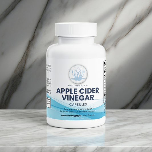 A white bottle of Balanced Bayou Apple Cider Vinegar Capsules, set on a light marble surface with a matching marble background.