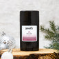 Black deodorant stick with a label on a wooden surface with decorative elements.